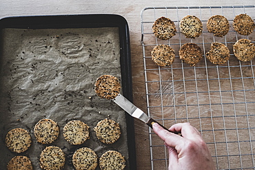 High angle close up of person removing freshly baked seeded crackers from a baking tray, England