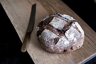 A loaf of freshly baked brown bread with a thick crust on a bread board, England