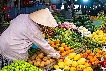 Vendor at his fruit and vegetable stall at a market in Hoi An, Vietnam