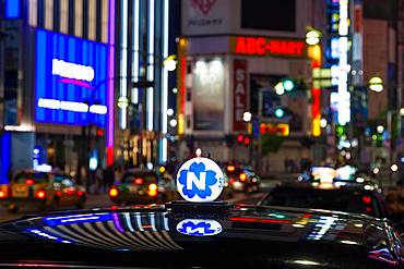 Roof of taxi and neon advertising signs at night in Shinjuku District, Tokyo, Japan