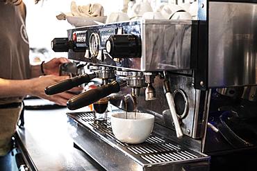 Close up of person making a cappuccino using commercial espresso machine