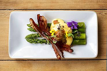 High angle close up of plate of green asparagus with crispy bacon and Hollandaise Sauce