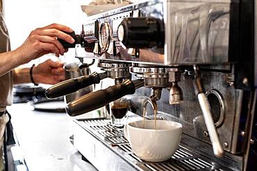 Close up of person making a cappuccino using commercial espresso machine