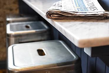 Close up of three stools at a bar counter, folded newspaper on top