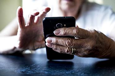 Close up of senior woman sitting at a table, using mobile phone