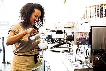 Woman barista preparing a cup of coffee in a coffee shop