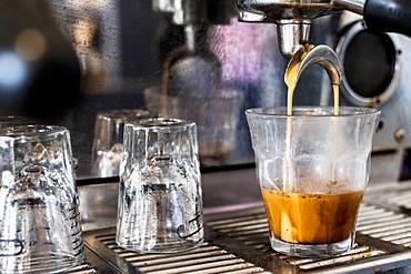 A commercial expresso machine in a coffee shop making an expresso shot