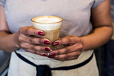 Woman barista preparing a cup of coffee in a coffee shop