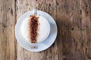 A cup of coffee in a cafe, a cappuccino with frothy top and sprinkled chocolate powder