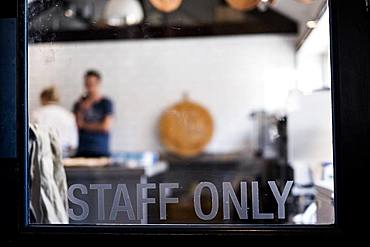 View through a door marked Staff Only to a commercial kitchen and two people working