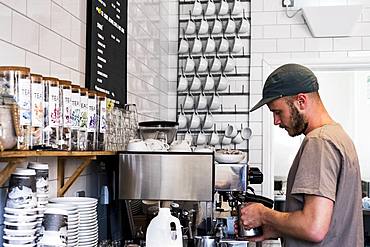 A man barista working a coffee machine in a cafe