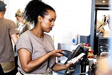 A woman using a touch screen till in a cafe