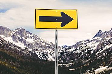 Directional arrow sign in a snow covered mountain range