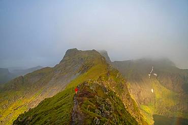 Walker in the mountains with clouds drifting from the peaks on Senja Island, Troms County, Senja Island, Lofoten Islands, Norway