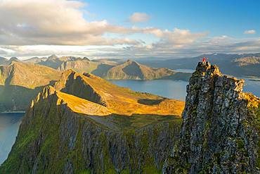 Man standing at the top of a pinnacle with a view over the landscape, Senja Island, Troms, Senja Island, Lofoten Islands, Norway