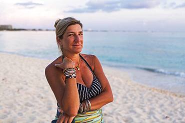 Adult woman looking at setting sun, Grand Cayman, Cayman Islands