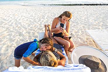 Mother and her children enjoying the beach at sunset, Grand Cayman, Cayman Islands