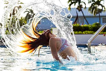 A teenage girl tossing her wet hair back, in pool, Grand Cayman, Cayman Islands