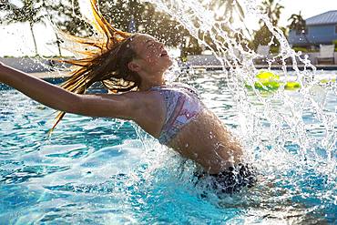 A teenage girl tossing her wet hair back in a swimming pool, Grand Cayman, Cayman Islands