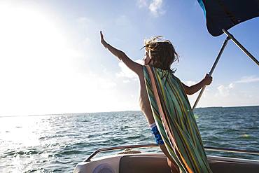 5 year old boy on the deck of a boat, leaning forward, Grand Cayman, Cayman Islands