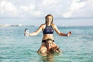 Adult woman standing in ocean water at sunset with her children, Grand Cayman, Cayman Islands