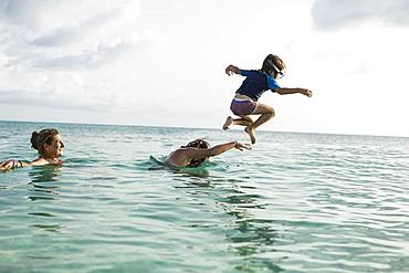 Adult woman standing in ocean water at sunset with her children, Grand Cayman, Cayman Islands