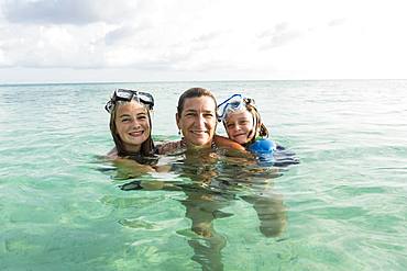 Adult woman standing in ocean water at sunset with her children, Grand Cayman, Cayman Islands