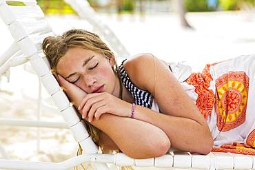 A teenage girl sleeping in beach chair, Grand Cayman, Cayman Islands