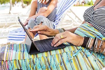 adult woman executive using laptop on the beach , Grand Cayman, Cayman Islands