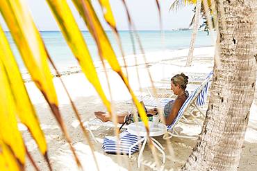 adult woman executive using laptop on the beach , Grand Cayman, Cayman Islands