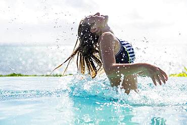 A teenage girl in infinity pool, tossing her hair back, Grand Cayman, Cayman Islands