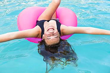 Smiling teenage girl in colorful floatie in a swimming pool, Grand Cayman, Cayman Islands