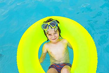 Smiling 5 year old boy in colorful floatie in the water, Grand Cayman, Cayman Islands