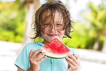 Smiling 5 year old boy eating watermelon slice, Grand Cayman, Cayman Islands