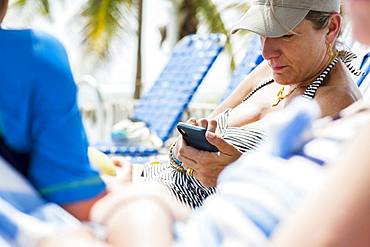 Woman texting on smart phone while on vacation, Grand Cayman, Cayman Islands