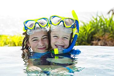 A teenage girl and her 5 year old brother in pool, smiling, Grand Cayman, Cayman Islands