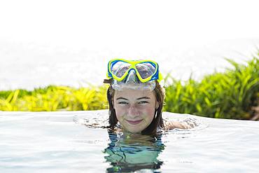 A teenage girl relaxing in a swimming pool, Grand Cayman, Cayman Islands