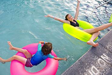 Siblings, brother and sister playing in pool with colorful floaties, Grand Cayman, Cayman Islands