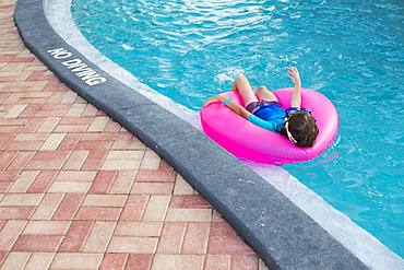 Siblings, brother and sister playing in pool with colorful floaties, Grand Cayman, Cayman Islands