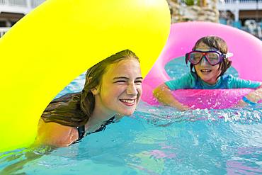 Siblings, brother and sister playing in pool with colorful floaties, Grand Cayman, Cayman Islands