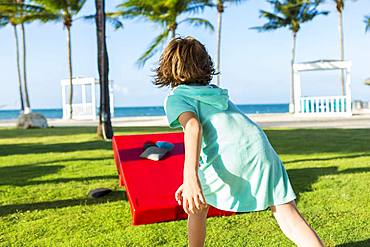 Rear view of 5 year old boy tossing beanbag, Grand Cayman, Cayman Islands