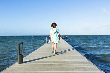 5 year old boy walking on a pier, view to the horizon, Grand Cayman, Cayman Islands