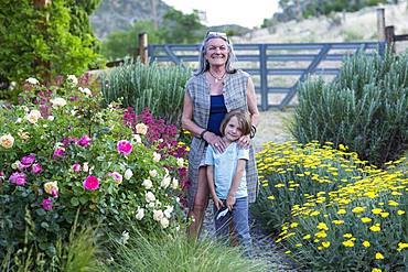 A senior adult, grandmother and her 5 year old grandson pruning roses in her garden