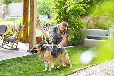 A teenage girl washing her dog on green lawn