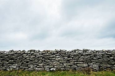 View of old dry stone wall under a cloudy sky