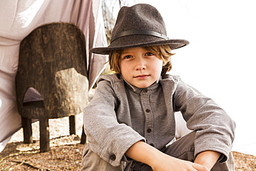 Six year old boy playing in an outdoor tent made of sheets