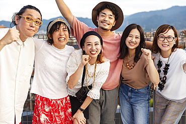 Smiling group of young Japanese men and women standing on a rooftop in an urban setting, Fukuoka, Kyushu, Japan