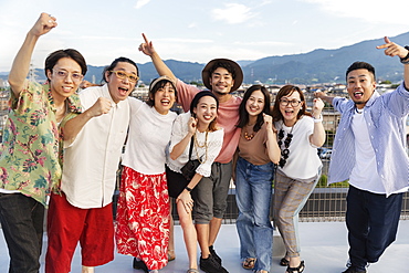 Smiling group of young Japanese men and women standing on a rooftop in an urban setting, Fukuoka, Kyushu, Japan