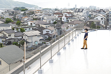 High angle view of Japanese man standing on a rooftop in an urban setting, Fukuoka, Kyushu, Japan