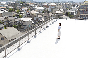 High angle view of Japanese woman standing on a rooftop in an urban setting, Fukuoka, Kyushu, Japan